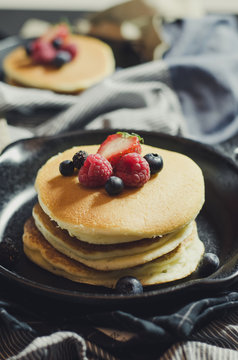 Home made pancakes with berries on metal frying pan decorated wi