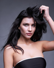 Fototapeta premium Portrait of a young brunette woman with long black streaming hai