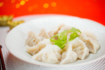 Chinese dumplings with sauce and white placemat on red background. People will eat dumplings during Chinese New Year to pray for good fortune.
