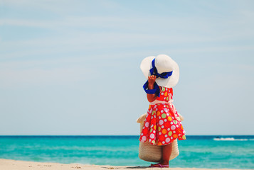 cute little girl with big bag and hat at sea