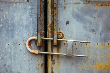 Close-up of rusty metal gate locked with security padlock