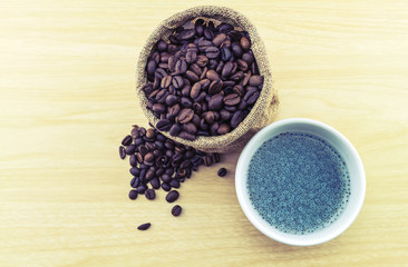 Sweet basil in white cup and coffee beans in sack sisal on wooden