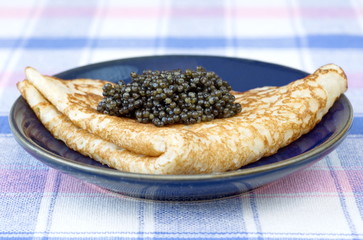 Pancakes with black caviar on plate
