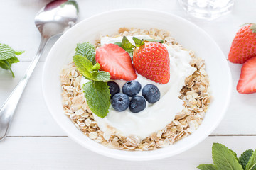 Morning healthy breakfast with muesli and berries on the white background. Side view