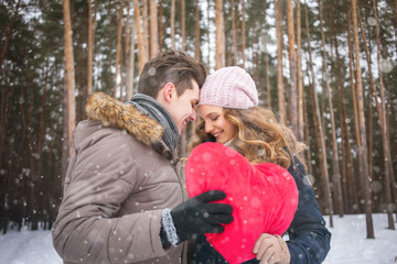 Obraz premium couple in the forest in winter, walk, kiss, hug and hold hands heart 