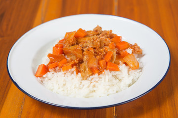 Curry on rice in plate on wood table