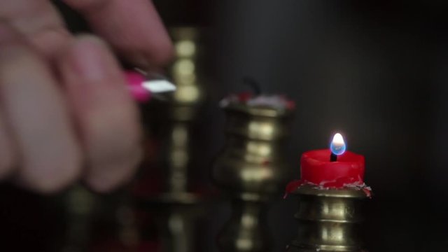 Color footage of a candle in a candlestick, and a hand lighting it with a lighter. 