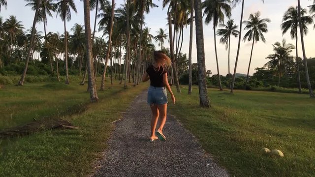 Fallow me. Young happy girl run at coconut plantation. Tourist woman feeling free near palm trees. HD slowmotion.