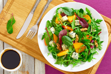 persimmon salad with lettuce leaves, blue cheese and walnuts
