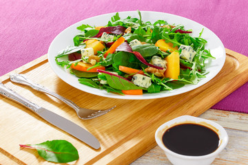 salad with persimmon slices, mix of lettuce leaves, blue cheese