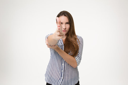 girl pointining finger gun at you and looking dangerous over white background isolated