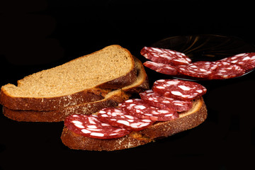 Smoked sausage and bread on a black background