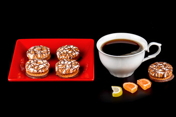 Cup of coffee, marmalade and chocolate chip cookies in a red plate on a black background.