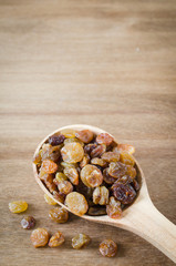 Dried Organic Raisins in a wooden Spoon on Rustic Background.