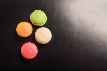 Multicolored macaroons falling or flying isolated on black background. Free space for text