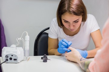 Professional beautician applying nail polish to female nail