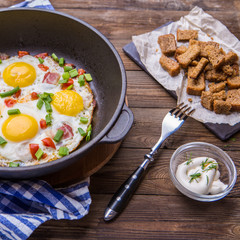 Fried eggs in pan with tomatoes and green fresh onion.