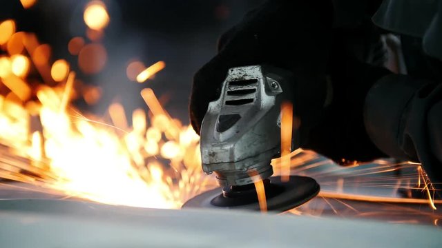 Car service - worker grinding metal construction with a circular saw, close up