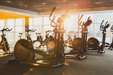 Modern gym interior with equipment, fitness exercise elliptical trainers