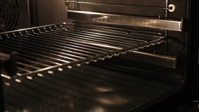 Slow tilt on greasy electric oven walls and grid lighted 4K 2160p 30fps UltraHD footage - Close-up of thermally insulated stove components 3840X2160 UHD tilting video 