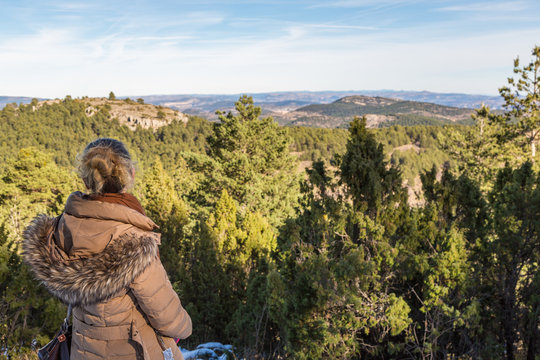 Kvinna tittar ut &ouml;ver bergslandskap fr&aring;n ett sn&ouml;t&auml;ckt berg
