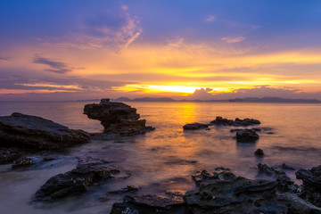 beautiful twilight sunset sky over sea with rocks in foreground