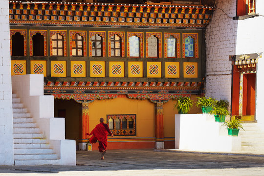 Young monk runs through courtyard in Paro Dzong, a fortress and Buddhist monastery, a sample of the traditional  architecture in the Kingdom of Bhutan.