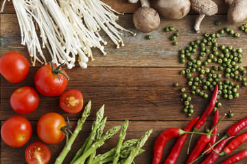 Fresh vegetable cooking ingredients on rustic wooden table with knife and brand new wooden chopping board