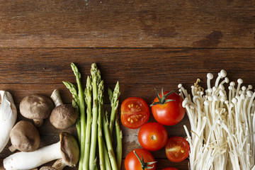 Fresh vegetable cooking ingredients on rustic wooden table with knife and brand new wooden chopping board