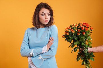 Angry offended woman standing and receiving bouquet of flowers