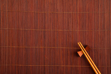 Two chopsticks on a bamboo mat.