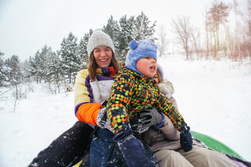 Happy smiling women and child on snow tubing