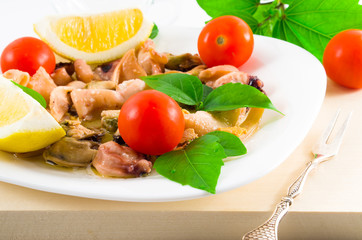 Salad of blanched pieces of seafood on a white plate close-up