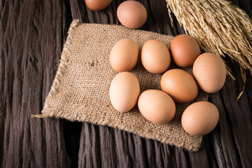 eggs and ear of rice on brown cloth on old wooden