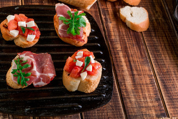 Set of bruschetta on black grill pan  wooden background. Tasty antipasto.