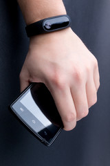 Men's hand with a fitness tracker and smartphone. Close up.