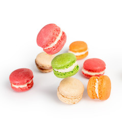 Different types of macaroons in motion falling or flying on white background. Traditional french dessert isolated
