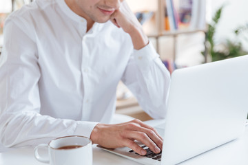 Cropped photo of man dressed in white shirt using laptop