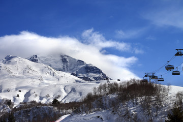 Fototapeta na wymiar Ski-lift, off-piste slope and mountain in clouds