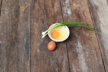 Raw egg in a bowl selective focus and onion on wooden table