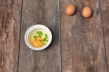 Raw egg in a bowl selective focus and onion on wooden table