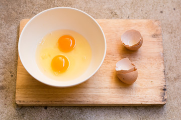 Raw egg in a bowl on wood borad