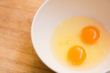 Raw egg in a bowl on wood borad