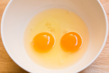 Raw egg in a bowl on wood borad