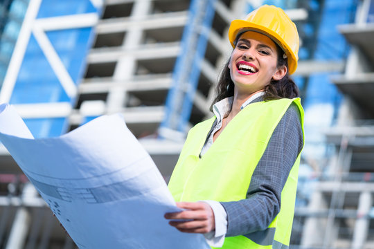 Female civil engineer studying drafts visiting construction site