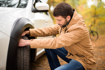 Man checking car tyre © LIGHTFIELD STUDIOS