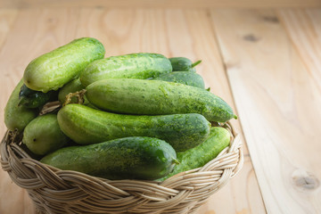 Fresh cucumbers in basket on wood