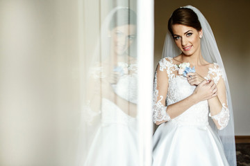 Charming bride holds blue flowers on her chest standing before g