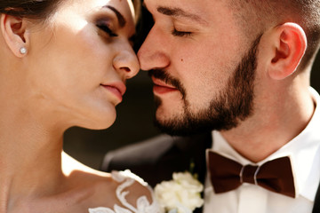 Tender touches of bride in lace dress and groom with red bow tie