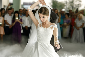 Naklejka premium Beautiful bride in lace dress whirls around groom dancing at the